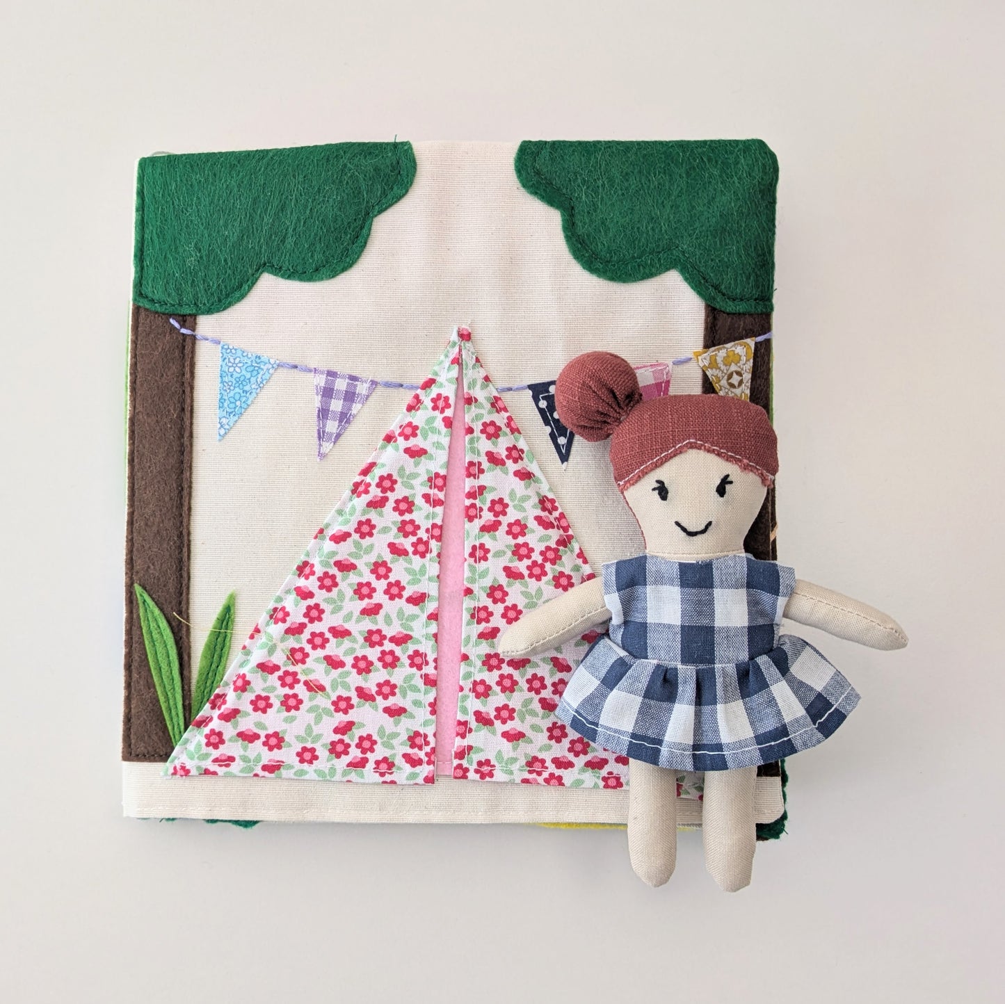 Fabric doll with a dress and a treehouse background on a white background