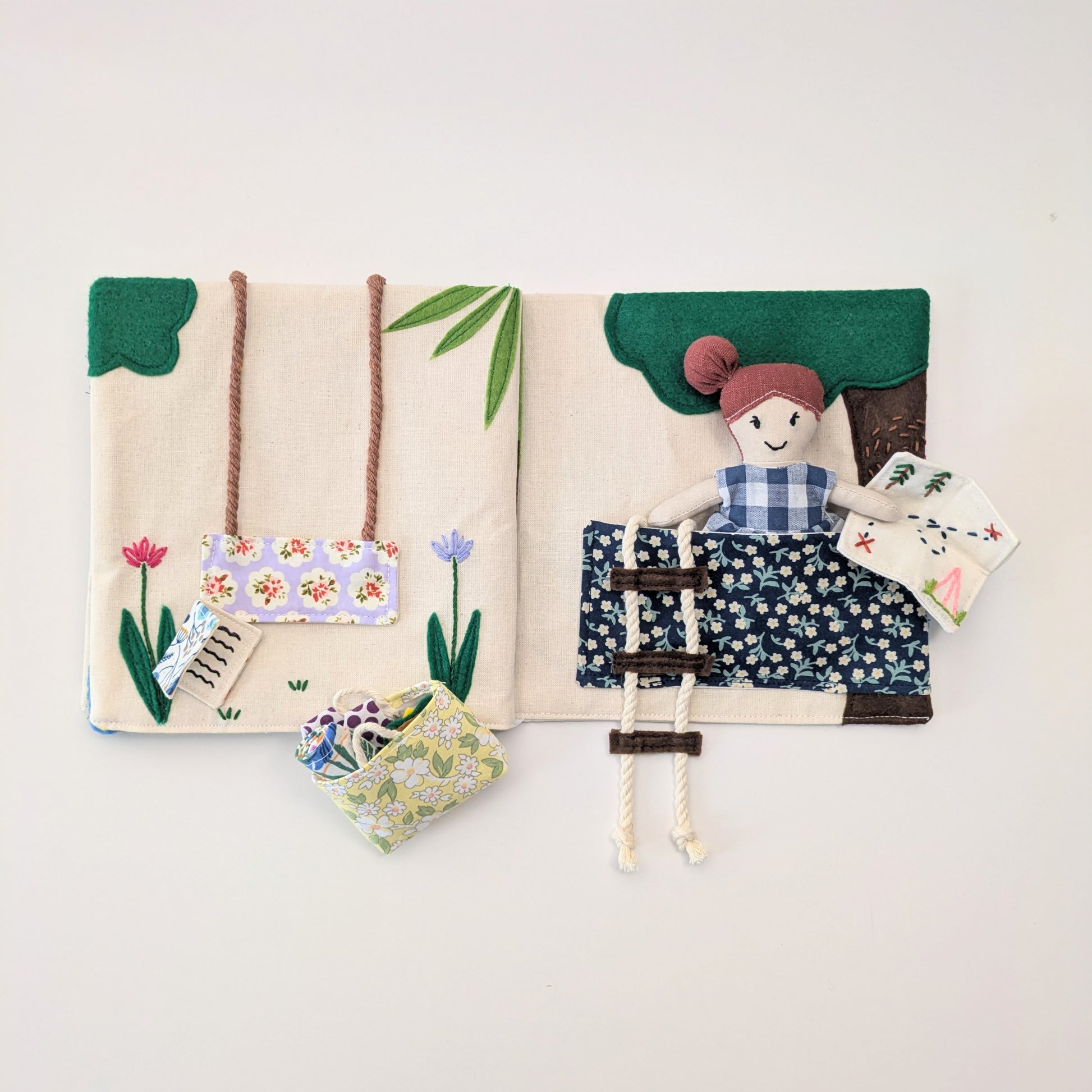 Fabric book with a character on a swing, flowers, and cards on a light background
