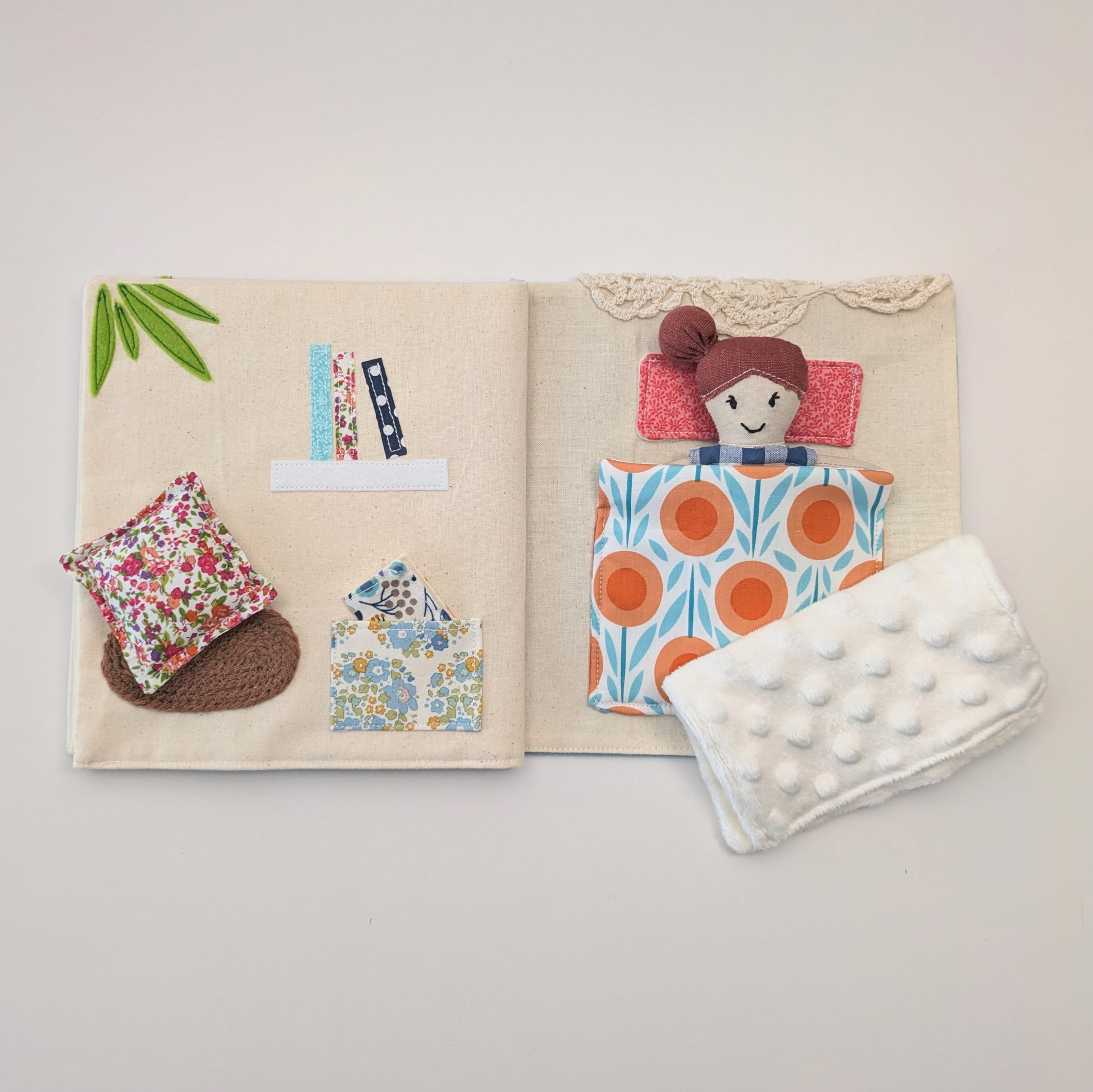 Open book with fabric samples and a soft toy on a light gray background